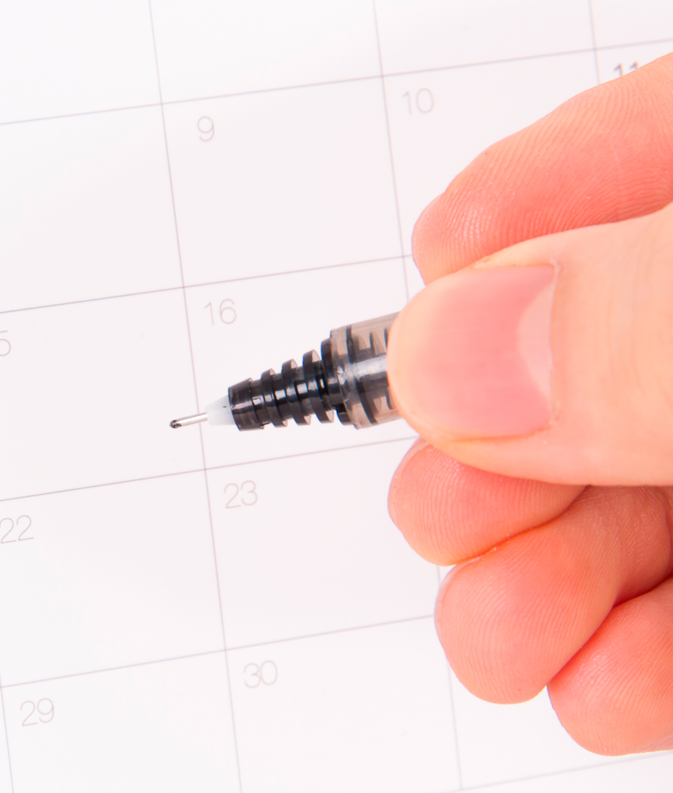 Vistas de una mano con un bolígrafo sobre una hoja de un calendario