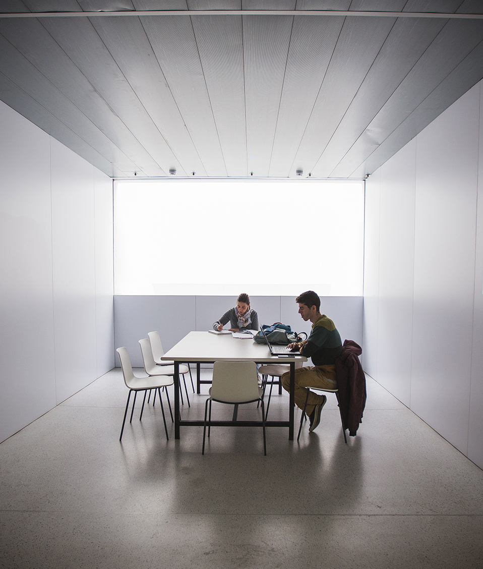 Dos estudiantes mirando apuntes en una mesa de estudio en el pasillo de la Facultad de Ciencias de la Salud