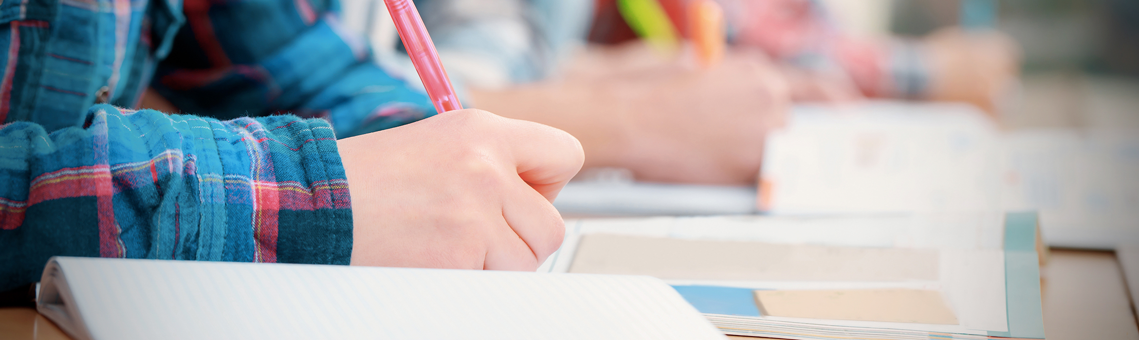 Estudiantes escribiendo apuntes mientras leen un libro