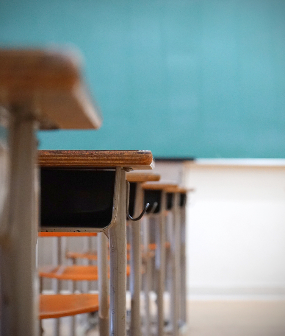 Interior de un aula de un colegio con pupitres y la pizarra al fondo